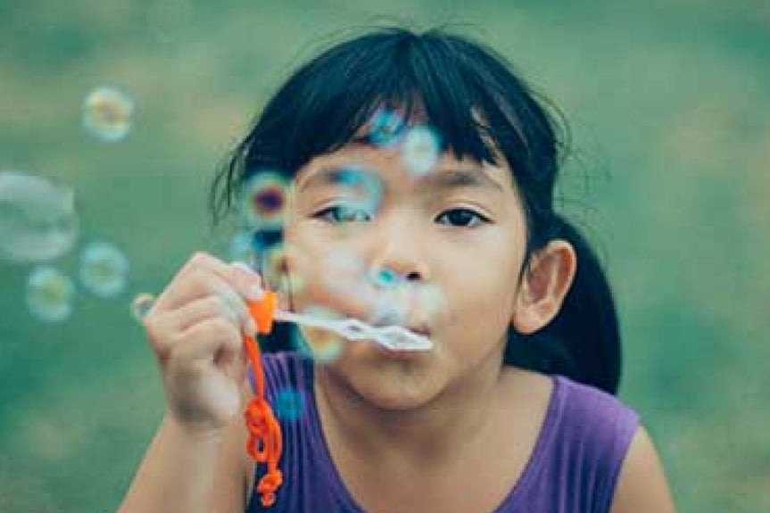 Low-resolution photo of girl blowing bubbles before upscale enhancement