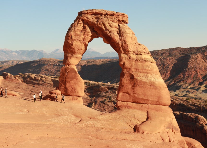 Before image of Delicate Arch with a person standing nearby on the left.