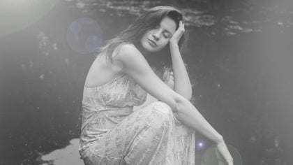 Woman in vintage dress sitting outdoors with a subtle retro lens flare effect