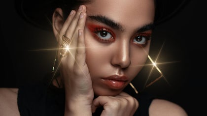 Woman with bold makeup and jewelry enhanced by dramatic lens flare highlights