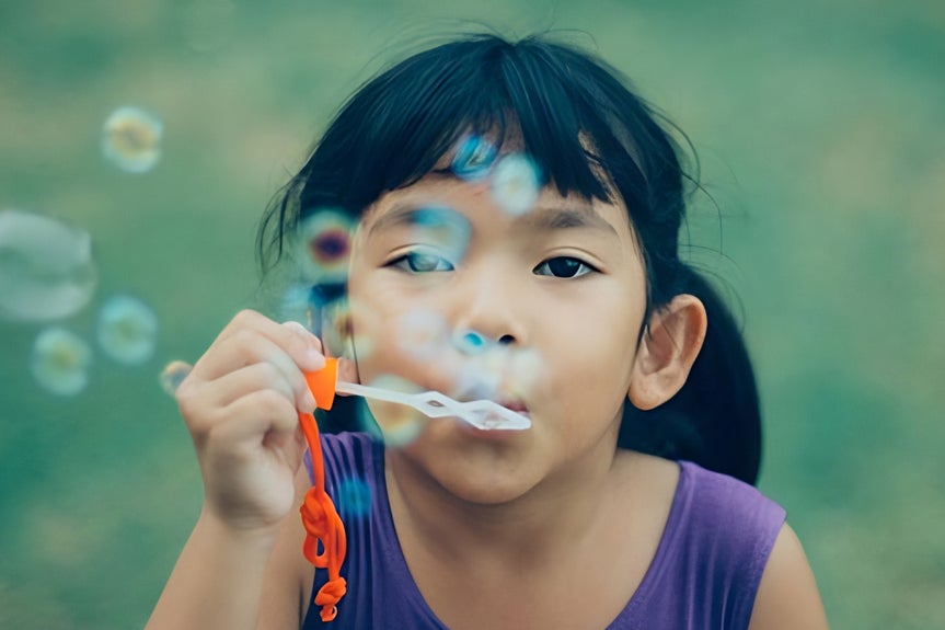 Clear and vibrant image of girl blowing bubbles after AI upscale improves quality